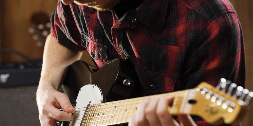 Gitar öğrenmek için alıştırma yapan öğrenci
